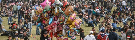 A balloon seller eating a hot-dog, while walking among the crowd, in the main arena at Download Festival